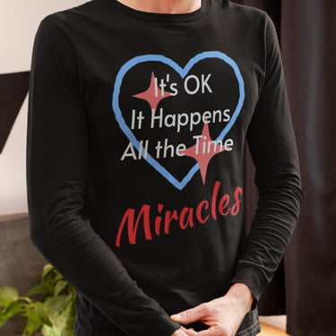 Long-sleeve Bella+Canvas t-shirt made from preshrunk ring-spun cotton with “Miracles Happen” design and message, “It’s OK. It Happens All the Time – Miracles,” faith-based apparel encouraging daily miracles through intimacy with God, man wearing long-sleeve black t-shirt